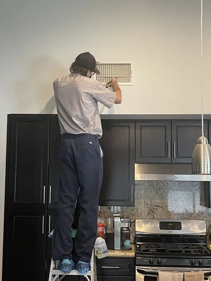 Technician inspecting an air vent during HVAC service in Macon